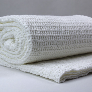 White honeycomb design blanket pictured rolled up on on grey background