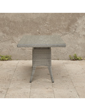 Six seater grey rattan garden table in front of stone wall view from end of table