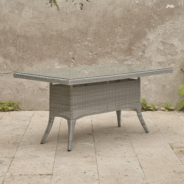 Six seater grey rattan garden table on an angle in front of stone wall