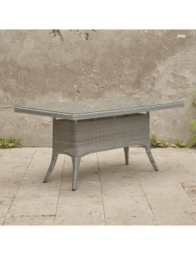 Six seater grey rattan garden table on an angle in front of stone wall