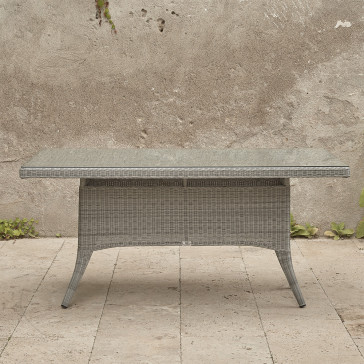 Six seater grey rattan garden table in front of stone wall