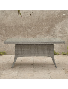 Six seater grey rattan garden table in front of stone wall