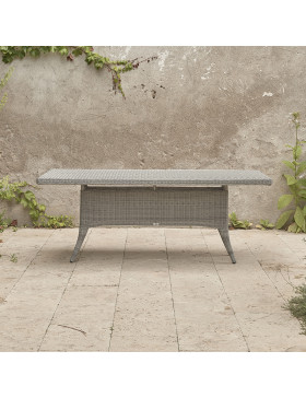 Eight seater grey rattan garden table in front of stone wall