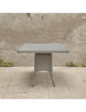 Eight seater grey rattan garden table in front of stone wall image from end of table