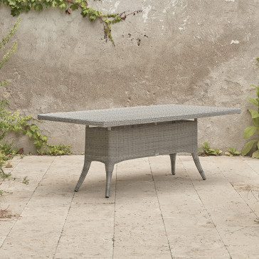 Eight seater grey rattan garden table at an angle in front of stone wall