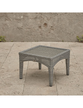 Compact garden rattan side table wirh tempered glass top pictured at an angle on a southern French terrace