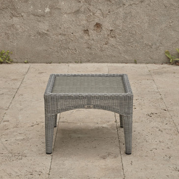 Compact garden rattan side table wirh tempered glass top pictured from the side on a southern French terrace