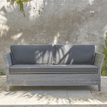 Two-seater rattan couch with UV resistant cushions in French grey on a southern French terrace