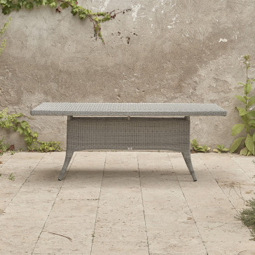 Eight seater Grey rattan garden table. On a terrace in front of stone wall