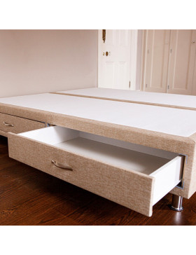 Divan bed base showing both drawers with one drawer open upholstered in an oatmeal furniture fabric pictured on a wooden floor